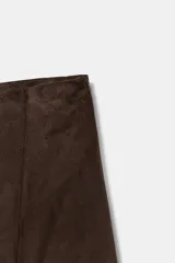 Falda midi de tiro medio con bajo asimétrico y cierre lateral con cremallera oculta. Presenta un acabado texturizado que simula el ante.
