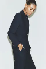 Blazer de cuello solapa y manga larga con cierre frontal de un botón. Presenta bolsillos delanteros con solapa y diseño estructurado.