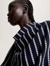 Blusa de poliéster azul marino con estampado de rayas verticales blancas. Tiene cuello abullonado y mangas largas.