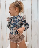 Conjunto de lycra con protección UV, estampado con hojas de palmera y animales de la selva. Incluye remera de manga larga con volados en los hombros y bombacha con volados en la cintura.