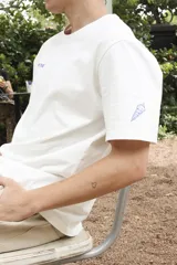 Remera blanca de algodón con estampado en la espalda con la frase "Follow the Waves" y dibujos de conchas marinas en color celeste.