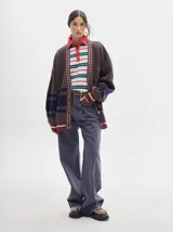Pantalón jean de tiro alto y corte pinzado, con perneras de caída suelta y levemente anchas en el bajo. Posee pasador con hebilla en la parte trasera.