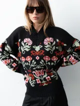 Buzo tejido de algodón negro con diseño jacquard de flores multicolor, cuello en V y mangas largas.