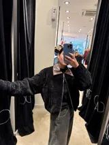 Chaqueta de pana negra con diseño acolchado, cierre frontal y cuello de solapa en cuero sintético marrón.