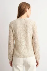 Blusa de encaje beige con escote en V y volados frontales, de manga larga.