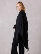 Ruana negra de tejido soft, con detalles de brillos y perlas en los extremos, y terminación con flecos.