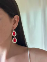 Aros colgantes plateados con dos gemas rojas facetadas en forma de lágrima.
