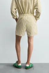 Shorts de hombre confeccionados en algodón con estampado de rayas verticales amarillas y blancas. Presenta cintura elástica, bolsillos frontales y un pequeño bordado de un pez en la parte inferior derecha.