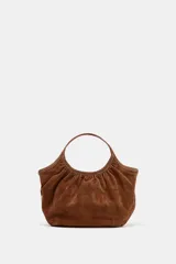 Bolso de hombro formato mini shopper confeccionado en piel, con diseño fruncido, doble asa de mano con pespuntes decorativos y cierre mediante clip metálico.