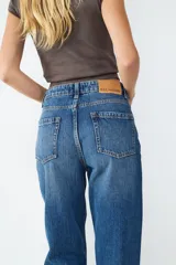 Jeans de tiro alto con corte recto, diseño clásico de cinco bolsillos, cierre frontal con cremallera y botón metálico.