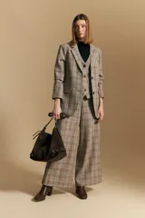 Blazer de corte sastrero con estampado de cuadros en tonos beige, marrones y rojizos. Presenta solapas clásicas, cierre frontal con un botón y bolsillos laterales con solapa.