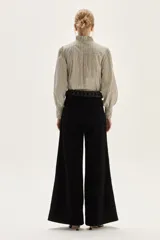 Jean de corte pata ancha color negro, con diseño de paneles frontales y bordados florales a lo largo de las piernas.