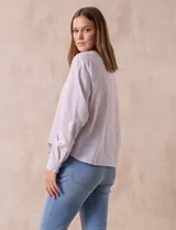 Blusa blanca de algodón marca Dash, con escote en V, abertura con botones, mangas 3/4 regulables con presilla y ruedo anudado.