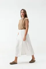 Falda midi de lino color beige, de tiro alto y corte recto, con abertura delantera y cierre cruzado sutil.