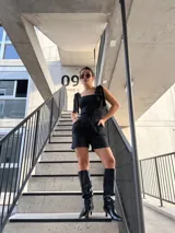 Top negro con estampado a rayas verticales blancas, breteles anchos con lazos en los hombros y corte ajustado.