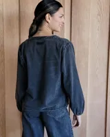 Blusa celeste de manga larga con escote en V y detalle bordado en el cuello.