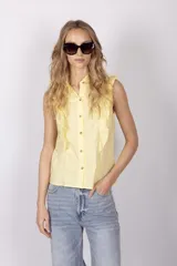 Blusa celeste sin mangas con cuello camisero y volados en los hombros.