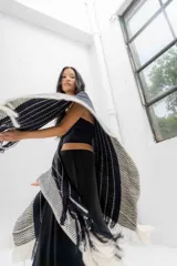 Ruana tejida en tonos azul marino y crudo, con diseño a rayas verticales y detalle de flecos en el ruedo. Presenta un patrón de espiga en los bordes.