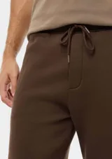 Pantalón babucha deportivo de felpa color gris melange, con cintura elástica ancha, cordones ajustables y puños en los tobillos.