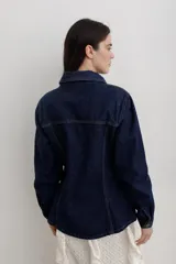Chaqueta de denim color marrón, con corte entallado en la cintura, cierre frontal con botones metálicos y bolsillos superiores con solapa.