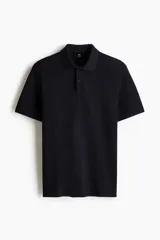 Remera polo de manga corta en piqué de algodón color negro, con cuello clásico y tapeta de dos botones. Corte estándar para una silueta clásica y cómoda.