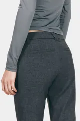 Pantalón sastrero gris oscuro de tiro alto, con corte acampanado, trabillas para cinturón y cierre frontal con cremallera y gancho oculto.