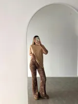 Pantalón tipo oxford de tiro alto con estampado animal print de leopardo, corte ajustado en la parte superior y acampanado desde la rodilla hacia abajo.