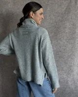 Sweater color crudo de cuello alto con mangas largas y corte holgado.