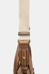 Bolso tipo mini shopper de cuero sintético color marrón caramelo, con costuras blancas visibles. Posee asas de mano y una correa bandolera ancha de tela color beige. El frente tiene un detalle de tira con hebilla metálica dorada.