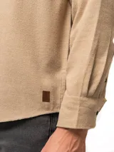Camisa de franela color azul marino, de manga larga, con cuello abotonado, un bolsillo frontal y cierre de botones.
