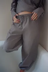 Pantalón bombacho de tiro medio con estampado de rayas verticales finas. Presenta cintura elástica con cordón ajustable, bolsillos laterales, costuras decorativas marcadas y bajo abullonado con elástico.