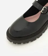 Zapato estilo Mary Jane de la marca Satinato, color negro, confeccionado en poliuretano con suela tractorada de goma, punta redonda y tira en el empeine con hebilla metálica ajustable.
