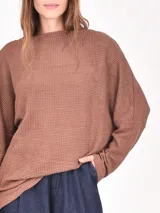 Buzo de tejido de punto tipo waffle en color negro, con cuello redondo, mangas largas y corte holgado.