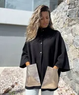 Saco tejido de punto en color negro, con corte holgado y mangas tres cuartos. Presenta bolsillos frontales amplios confeccionados en cuero metalizado color plateado y cierre frontal con botones.