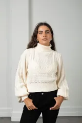 Polera de punto color blanco con cuello alto, mangas globo y diseño de trenzas y calados en el frente.