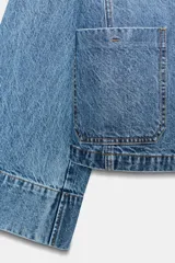 Campera de denim azul con cuello solapa, cierre frontal de botones metálicos, bolsillos delanteros de plastrón y mangas largas acampanadas.