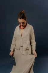 Pollera larga de lino color gris topo, de diseño amplio con volumen, movimiento y bolsillos delanteros. Cuenta con elástico en la cintura y detalles de pinzas y sobretelas en los laterales.