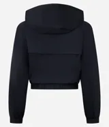 Campera rompevientos deportiva cropped de color blanco, con capucha, cierre frontal y puños elásticos. Confeccionada en poliamida, presenta un diseño ligero y funcional.