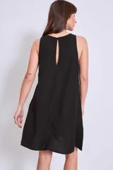 Vestido negro de corte holgado y largo a la rodilla, con cuello redondo y sin mangas. Presenta bordados florales en el escote y bolsillos laterales.