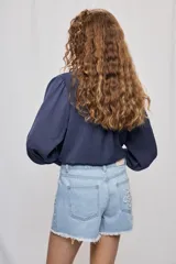 Short de denim blanco de calce recto y tiro medio, con bolsillos delanteros, cierre con botón y terminación desflecada en el ruedo. Presenta detalles florales bordados al tono en el frente.