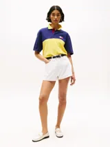 Chomba Tommy Hilfiger de corte amplio, con diseño color block en azul y amarillo, cuello clásico, cartera de tres botones, logo bordado en el pecho y logo oversize en la espalda.