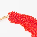 Collar tipo gargantilla compuesto por múltiples hilos de pequeñas cuentas de vidrio en color rojo intenso, con cierre de mosquetón y cadena de extensión en tono dorado.