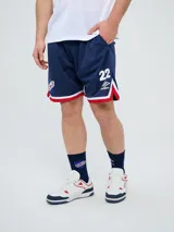 Short deportivo Umbro del Club Nacional de Football, modelo Match para hombre. Diseño en color azul marino con tejido de malla, detalles en blanco y rojo en los laterales y el escudo del club bordado.