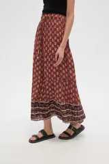 Falda larga de viscosa con estampado en tonos terracota y beige. Presenta un diseño escalonado con un patrón floral repetitivo en la parte principal y un borde inferior con un patrón geométrico en tonos más oscuros. Tiene cintura elástica con cordón ajustable.