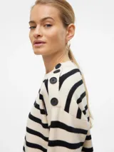 Sweater de punto con diseño de rayas horizontales en color crema y negro. Presenta cuello redondo, mangas largas y detalle de botones en uno de los hombros. El diseño es de calce regular con puños y ruedo acanalados.