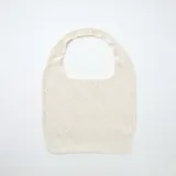 Bolso tipo tote color beige con diseño de tejido de punto calado y rombos, de asa corta integrada.