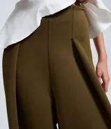 Pantalón de corte barrel color verde oliva, con cintura alta, pliegues delanteros y pernera ancha. Confeccionado en tejido con caída estructurada.