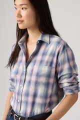 Camisa de franela Levi's con estampado de cuadros en tonos azul, rosado y crema. Presenta cuello clásico, cierre frontal con botones, mangas largas y un bolsillo en el pecho con la etiqueta roja característica de la marca.