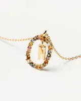 Collar dorado con dije ovalado con incrustaciones de piedras de colores y letra N colgante.