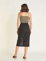 Falda midi color beige, de tiro alto con elástico en la cintura trasera, cierre y botón delantero. Tiene bolsillos delanteros y bolsillos cargo a los costados, con tajo en el delantero.